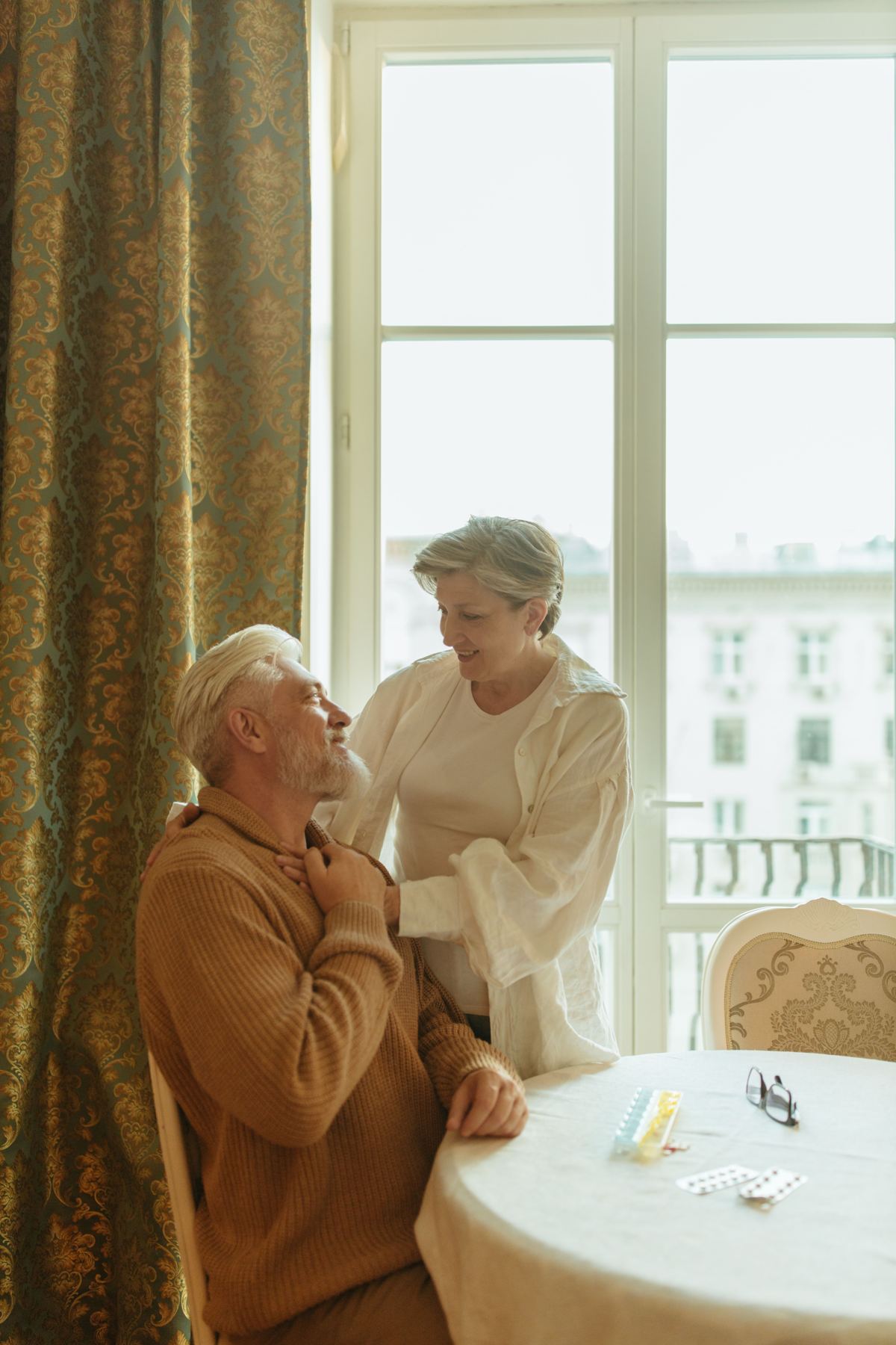 A caregiver smiling with a senior man at his kitchen table