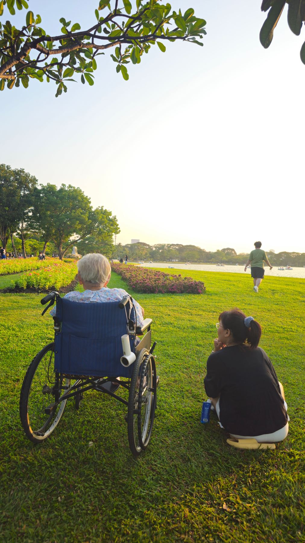 A caregiver sitting with an senior woman in a wheelchair at the park