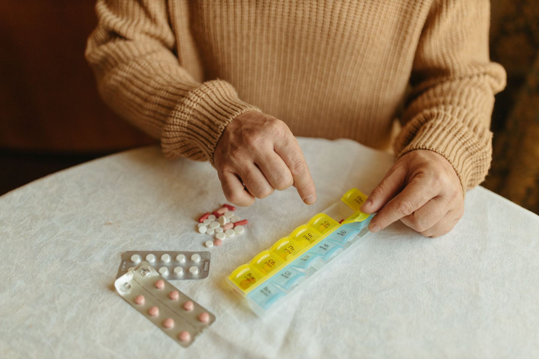 A senior man sorting a weekly pill organizer at his table